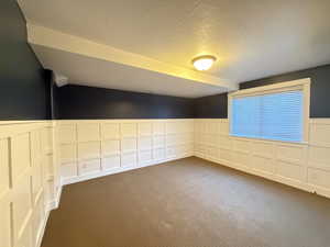 Bedroom 4/5 Unfurnished room featuring a wainscoted wall,  dark colored carpet, 2 closets and a larger window.