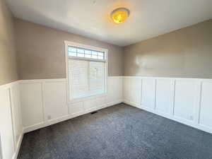 Bedroom 1/5 with a wainscoted wall, dark gray carpet, a wider closet, 9 ft ceilings