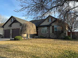 View of front facade with stone and  stucco siding, and concrete driveway in the evening sunset.