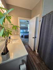Ensuite bathroom with vanity, a shower with curtain, larger linen closet and LVP floors. The bathroom has newer custom Jensen's cabinet and quartz countertop.