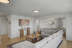 Living area featuring light wood-type flooring, hanging lights, and a textured ceiling