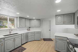 Kitchen featuring gray cabinetry, light wood-style floors, stainless steel appliances, recessed lighting, and a textured ceiling