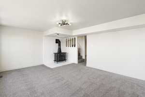 Unfurnished living room with a wood stove and carpet floors