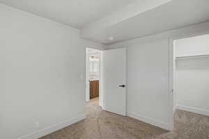 Unfurnished bedroom featuring light carpet and a walk in closet