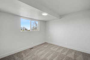 Spare room with baseboards and light colored carpet
