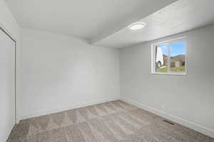 Empty room with light colored carpet and baseboards