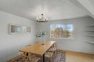 Dining area with light wood-style flooring, a textured ceiling, and a chandelier