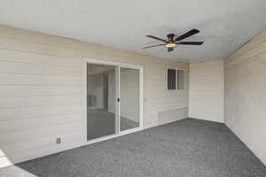 Unfurnished sunroom with ceiling fan and a patio area