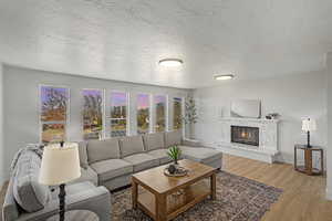 Living area with a textured ceiling, wood finished floors, and a glass covered fireplace