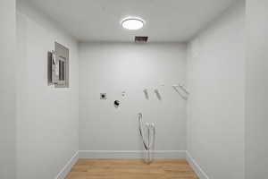 Laundry area featuring hookup for a washing machine, light wood-style flooring, hookup for an electric dryer, and electric panel