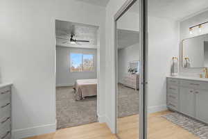Full bathroom featuring vanity, ensuite bath, light wood-style floors, a textured ceiling, and light carpet
