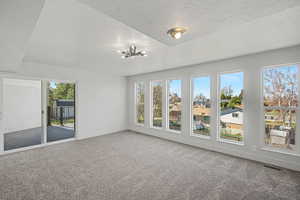 Carpeted spare room featuring a textured ceiling and hanging lights