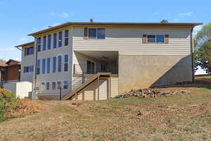 Rear view of property featuring a lawn and a ceiling fan