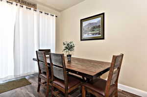 Dining space with dark wood-type flooring and baseboards
