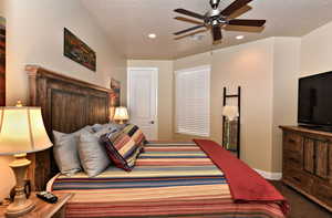 Carpeted bedroom with a ceiling fan, a textured ceiling, and recessed lighting
