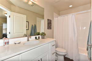 Bathroom with vanity, shower / bathtub combination with curtain, and dark wood-style flooring