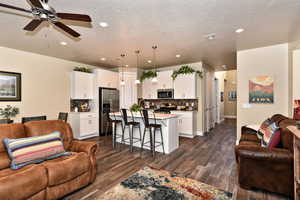 Living area with dark wood-style flooring, a ceiling fan, a textured ceiling, and recessed lighting