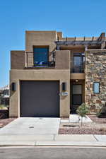 View of front of house with a balcony, stucco siding, concrete driveway, and a garage