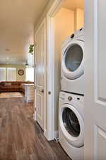 Laundry area featuring dark wood-style flooring and stacked washer and clothes dryer
