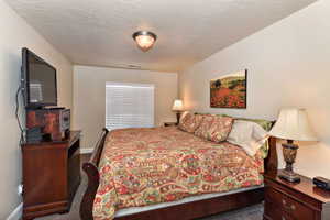 Bedroom featuring a textured ceiling and dark carpet