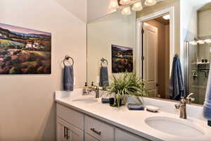 Bathroom featuring double vanity and tiled shower