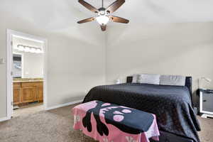 Bedroom with light colored carpet, ceiling fan, ensuite bath, and lofted ceiling