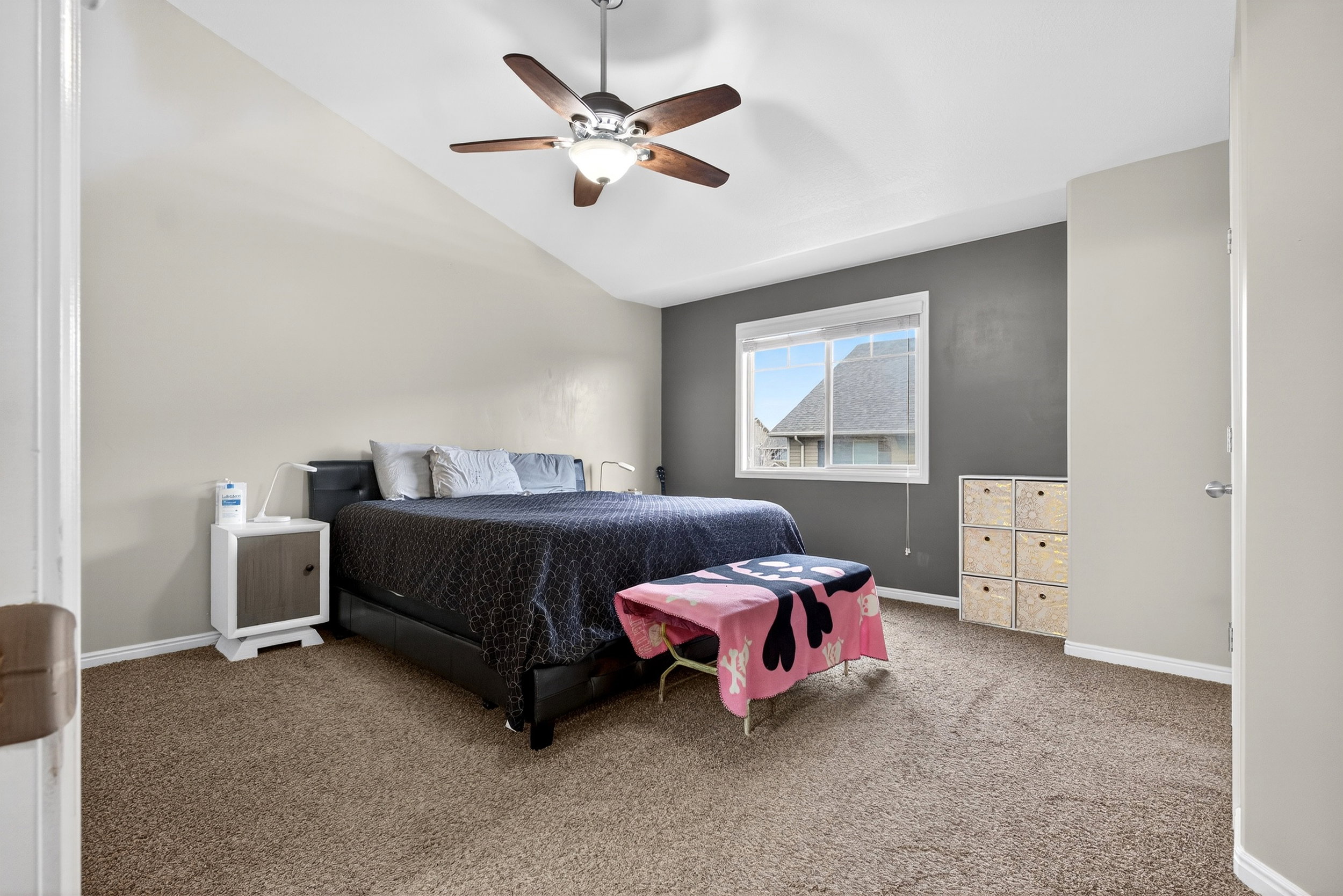Carpeted bedroom featuring vaulted ceiling and ceiling fan