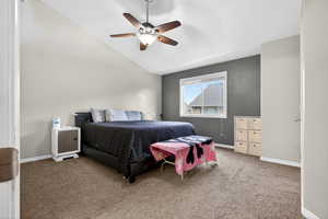 Carpeted bedroom featuring vaulted ceiling and ceiling fan