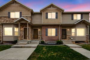 View of front of property with a lawn and stone siding