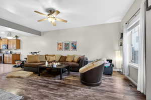 Living area featuring dark wood-type flooring and ceiling fan
