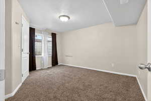 Unfurnished bedroom featuring a textured ceiling and dark carpet