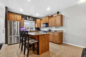 Kitchen with dark stone countertops, stainless steel appliances, wood finish cabinetry, and recessed lighting