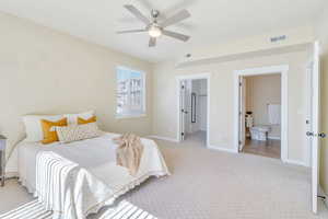 Bedroom featuring a walk in closet, light colored carpet, a ceiling fan, and connected bathroom