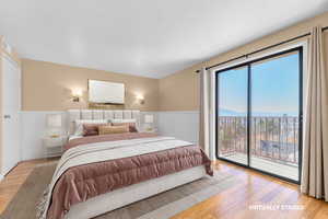 Bedroom with access to exterior, light wood-style floors, wainscoting, and a mountain view