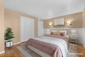 Bedroom featuring light wood-type flooring, a closet, and a wainscoted wall