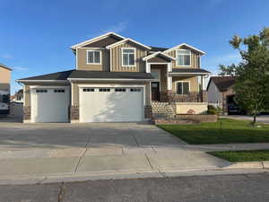Craftsman-style house with board and batten siding, concrete driveway, covered porch, and stone siding