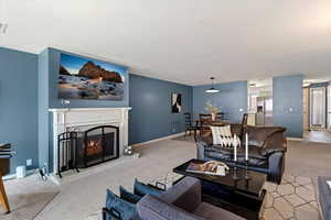 Living area with light carpet and a warm lit fireplace