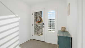 Entryway featuring light carpet and baseboards