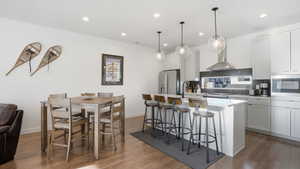 Kitchen featuring an island with sink, white cabinetry, a kitchen breakfast bar, and tasteful backsplash