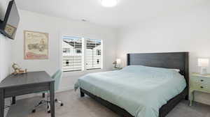 Carpeted bedroom with baseboards and a desk