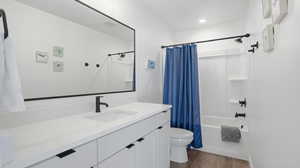 Full bath with vanity, dark wood-style flooring, and shower / tub combo