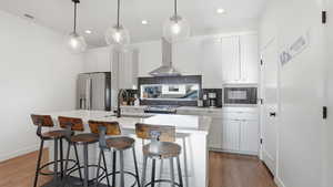 Kitchen with a breakfast bar area, tasteful backsplash, a kitchen island with sink, white cabinets, and stainless steel appliances