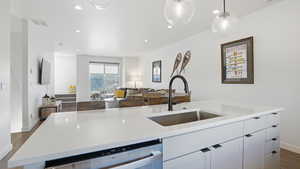 Kitchen with open floor plan, white cabinets, a Quartz kitchen island with sink, dishwasher, and decorative light fixtures