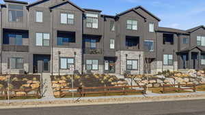 View of front of property featuring stone siding, board and batten siding, and a balcony