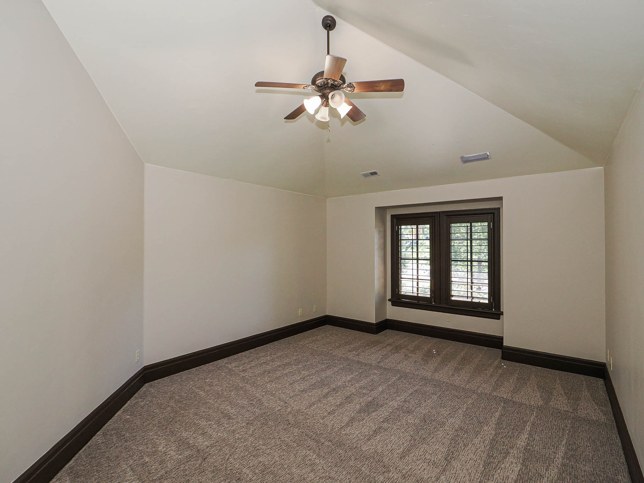 Unfurnished room featuring a ceiling fan, dark carpet, and lofted ceiling