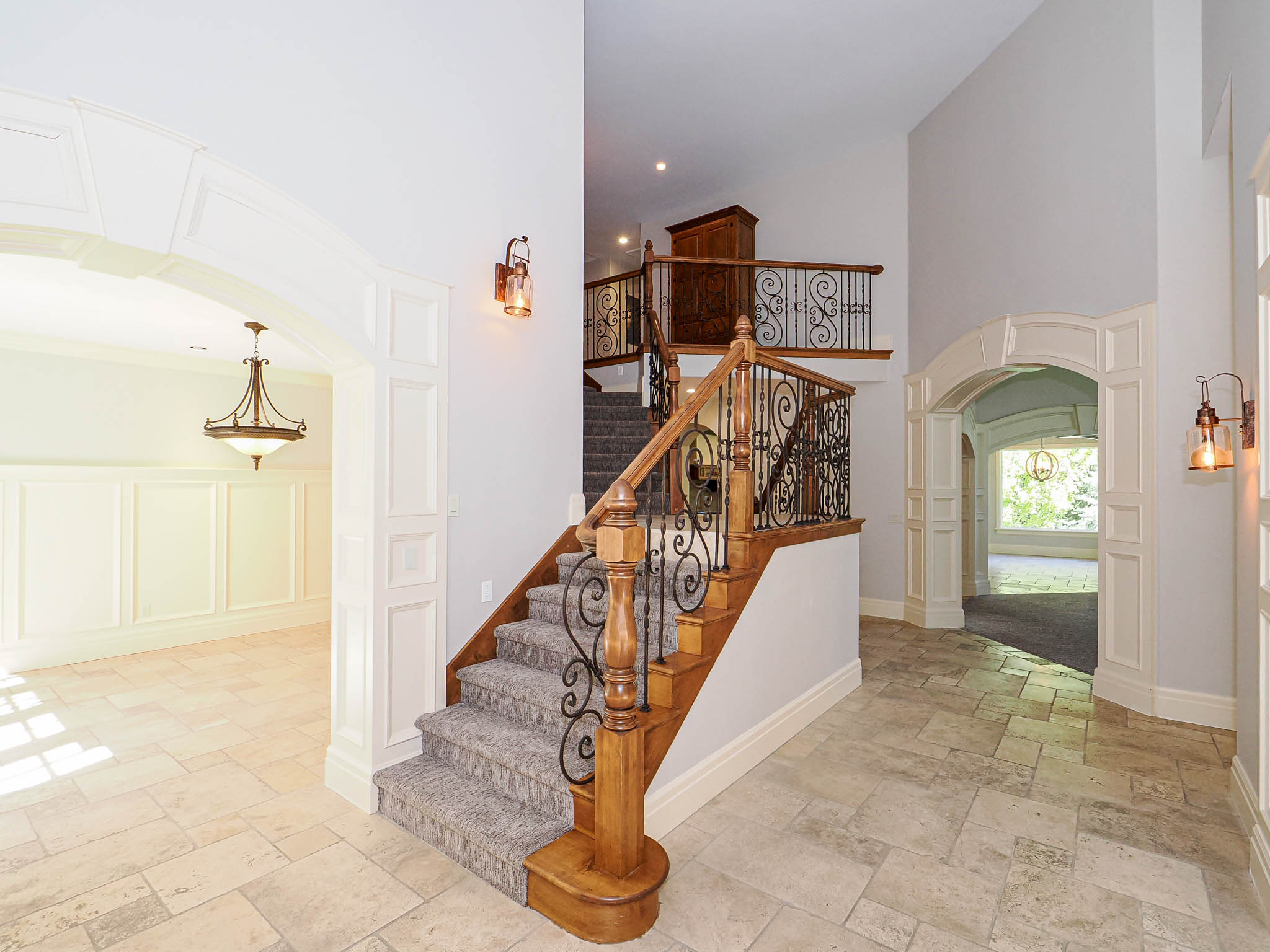 Stairs featuring arched walkways, a high ceiling, stone tile floors, decorative columns, and a decorative wall