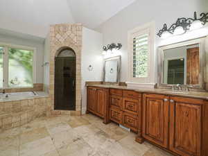 Bathroom featuring double vanity, a stall shower, a bath, and stone tile flooring
