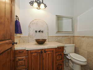 Half bath featuring vanity, tile walls, and wainscoting