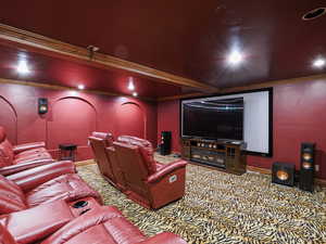 Home theater with ornamental molding and carpet