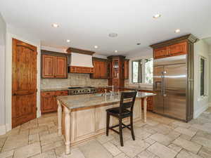 Kitchen with stainless steel appliances, light stone counters, recessed lighting, a breakfast bar, and stone tile flooring
